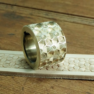 Peut inclure: Un outil de marquage en cuir en laiton avec un motif floral. L'outil est utilis&eacute; pour cr&eacute;er des motifs d&eacute;coratifs sur le cuir.