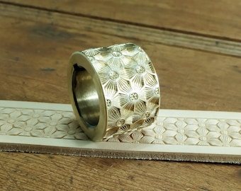 May include: A brass leather stamping tool with a floral design. The tool is used to create decorative patterns on leather.