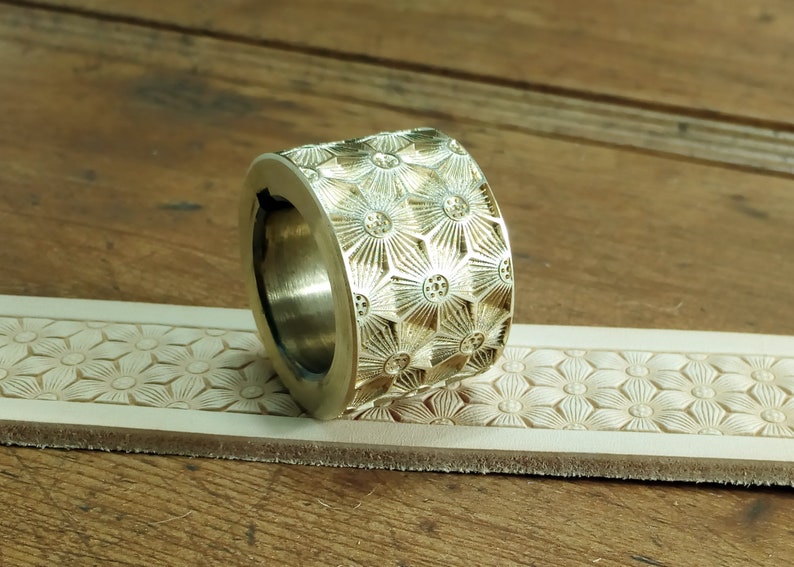 Peut inclure: Un outil de marquage en cuir en laiton avec un motif floral. L'outil est utilis&eacute; pour cr&eacute;er des motifs d&eacute;coratifs sur le cuir.