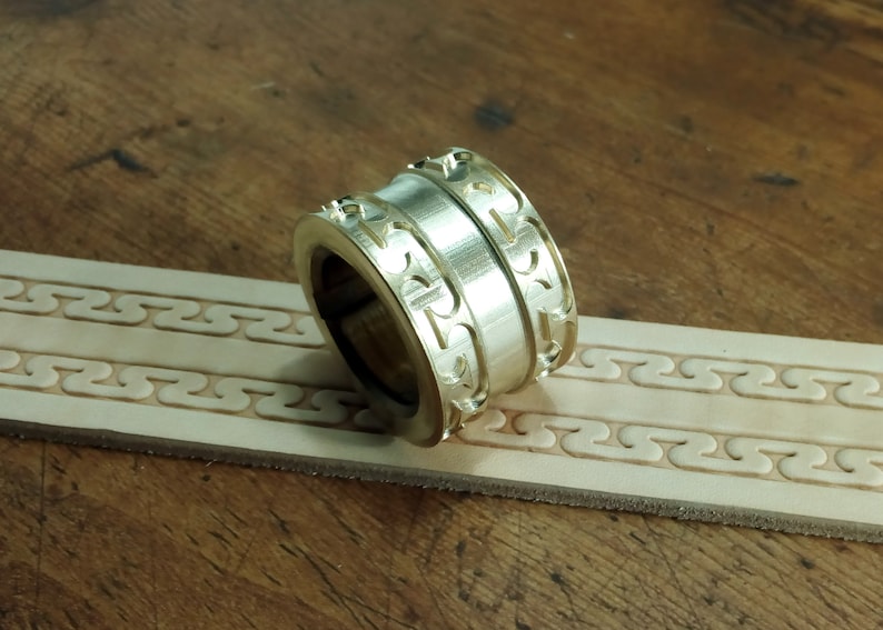 May include: A brass leather stamping tool with a decorative pattern. The tool is designed to create a repeating pattern on leather.