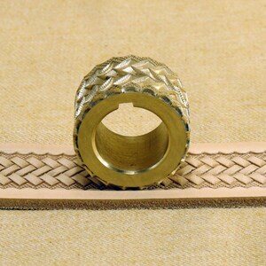 May include: A brass leather stamping tool with a diamond pattern design. The tool is being used to create a braided pattern on a piece of leather.