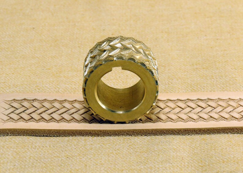 May include: A brass leather stamping tool with a diamond pattern design. The tool is being used to create a braided pattern on a piece of leather.