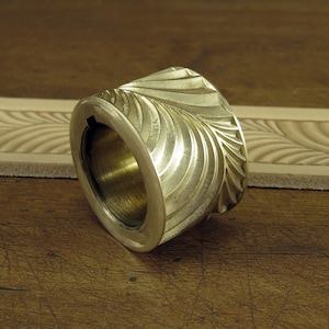 Pu&ograve; includere: Un rullo in ottone per la lavorazione del cuoio con un motivo a foglie vorticose. Il rullo &egrave; progettato per creare un bordo decorativo sul cuoio.