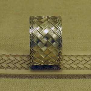 May include: A metal stamp with a geometric pattern of squares and diamonds. The stamp is used to create a decorative design on leather.