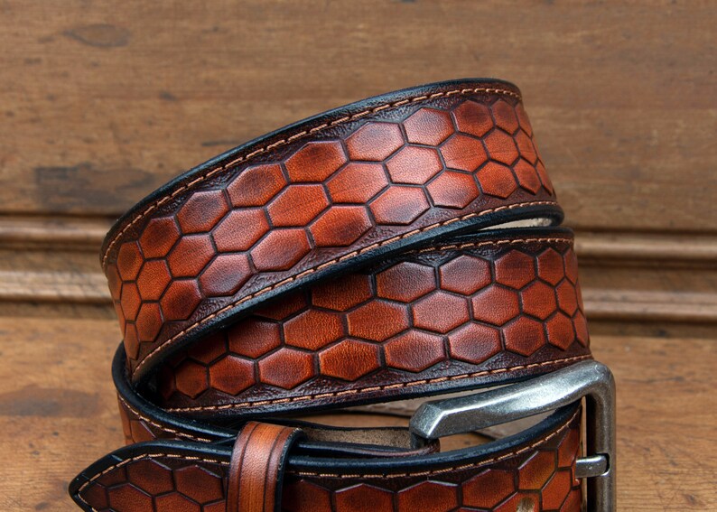May include: A brown leather belt with a honeycomb pattern and a silver buckle. The belt is folded in half and the buckle is visible.