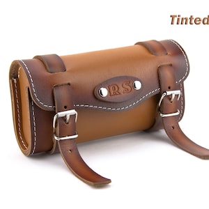 May include: Tinted Tan leather motorcycle saddlebag with a buckle closure and the initials "ORS" embossed on the front.