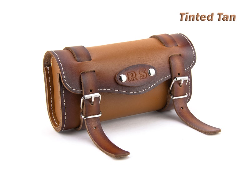 May include: Tinted Tan leather motorcycle saddlebag with a buckle closure and the initials "ORS" embossed on the front.