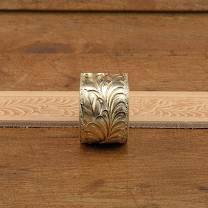 May include: A gold-colored metal belt buckle with an intricate floral design.