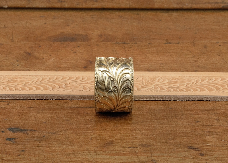 May include: A gold-colored metal belt buckle with an intricate floral design.