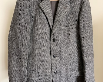 May include: A gray herringbone tweed blazer with a button closure and two flap pockets.