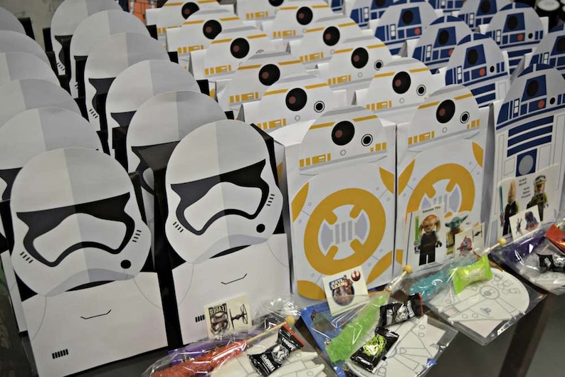 Puede incluir: Una colecci&oacute;n de cajas de regalo para fiestas con tem&aacute;tica de Star Wars con personajes como Stormtroopers y BB-8. Las cajas est&aacute;n llenas de peque&ntilde;os juguetes y golosinas.