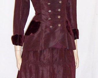 May include: A maroon dress with a velvet trim and a double-breasted jacket with silver buttons.