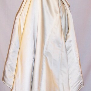May include: A white satin cape with a green satin collar over a teal satin skirt with gold embroidery.