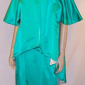 May include: A teal satin dress with a high neckline and short sleeves. The dress has a fitted bodice and a flowing skirt with gold embroidery.