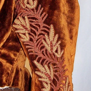 May include: A brown velvet jacket with gold and red embroidered floral designs on the sleeve.