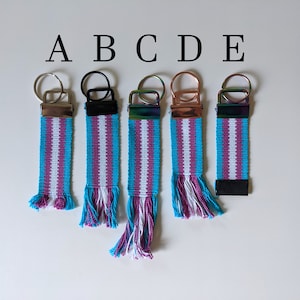 May include: Five keychains with a blue, white, and purple striped design. The keychains have different colored metal rings. The keychains are labeled A, B, C, D, and E.