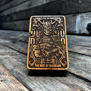 Peut inclure: Une boîte en bois avec une image gravée d'un samouraï guerrier au visage de crâne. La boîte est gravée des mots "Principe du Bushido" et "La Voie du Guerrier".
