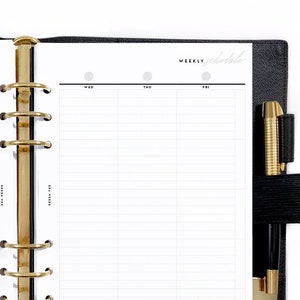 May include: A black leather bound planner with gold rings and a white weekly schedule page. The page has a grid layout with columns for each day of the week. A black pen is attached to the planner.