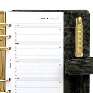 May include: A black leather bound planner with gold rings and a white page open to a contact list. The page has the heading "CONTACT info" and several lines for names, phone numbers, and addresses.