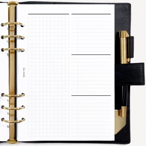 May include: A black leather planner with gold rings and a white page with a grid pattern on the left side and a lined page on the right side. The planner has a pen holder with a gold pen and a black pen.