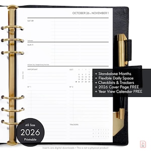 May include: Black A5 size 2026 printable planner with gold-colored metal rings and pen holder. The planner is open to a page with a calendar and the text "October 26 to November 1". Additional text includes "Standalone Months" and "Checklists & Trackers".