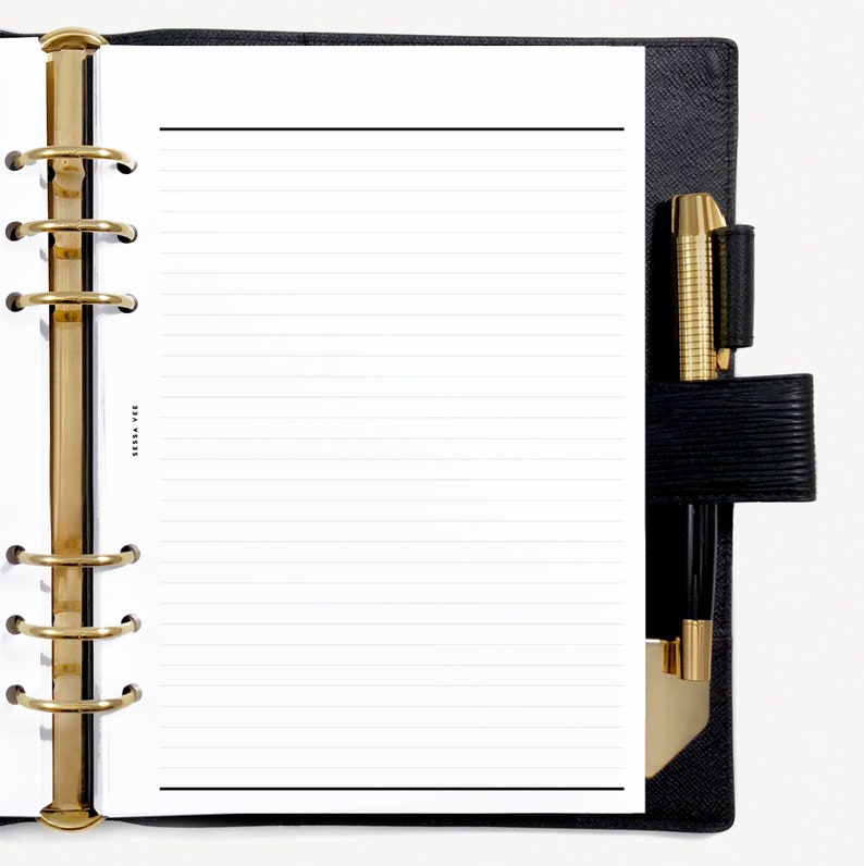 May include: A black leather bound planner with gold rings and a white lined page. A gold pen is in the pen holder.