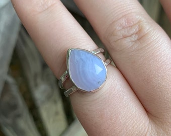May include: A silver ring with a teardrop-shaped blue agate stone.