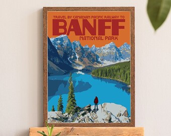 May include: A vintage travel poster with a retro design featuring a scenic view of a lake and mountains. The poster is framed in wood and has the text "TRAVEL BY CANADIAN PACIFIC RAILWAY TO BANFF NATIONAL PARK".