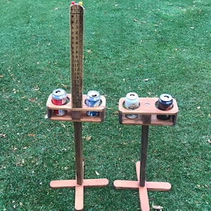 May include: Two wooden beer pong game sets with a scorekeeping board. Each set has a wooden base with four slots to hold cans. The scorekeeping board has numbers 1 through 20.