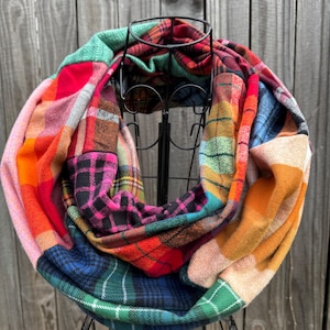 May include: A colorful infinity scarf made from patchwork plaid fabric in shades of red, orange, green, blue, pink, and black.