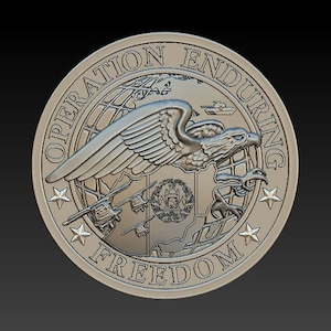 May include: A silver coin with the words "Operation Enduring Freedom" around the edge. The center of the coin features a bald eagle with wings spread, flying over a globe with a map of Afghanistan. There are three helicopters flying in formation below the eagle.