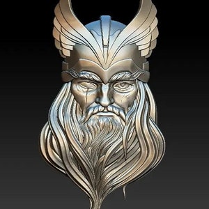 May include: A silver-colored sculpture of a man's head with a long beard and a winged helmet. The man has a serious expression and one eye is closed.