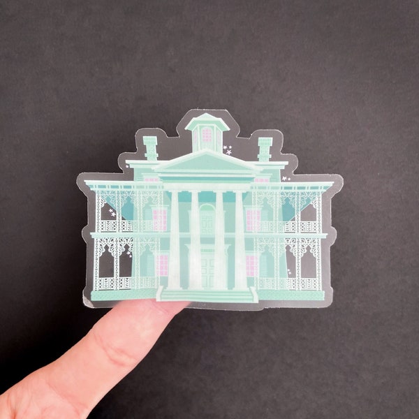 May include: A clear sticker of the Haunted Mansion from Disneyland. The sticker is a light green colour with white details and pink accents.