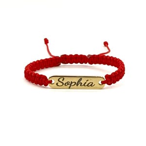 May include: Red string bracelet with a gold nameplate that says "Sophia".