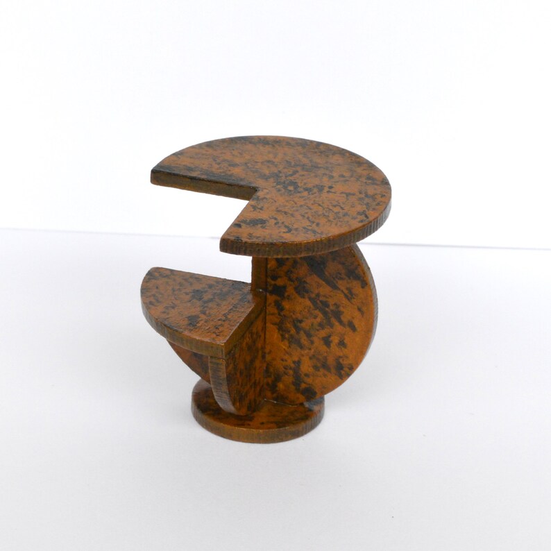 Puede incluir: Una mesa peque&ntilde;a de madera con un dise&ntilde;o geom&eacute;trico &uacute;nico. La mesa est&aacute; hecha de varias piezas de madera que se unen para crear una forma de espiral. La mesa est&aacute; pintada de color marr&oacute;n con un acabado moteado.