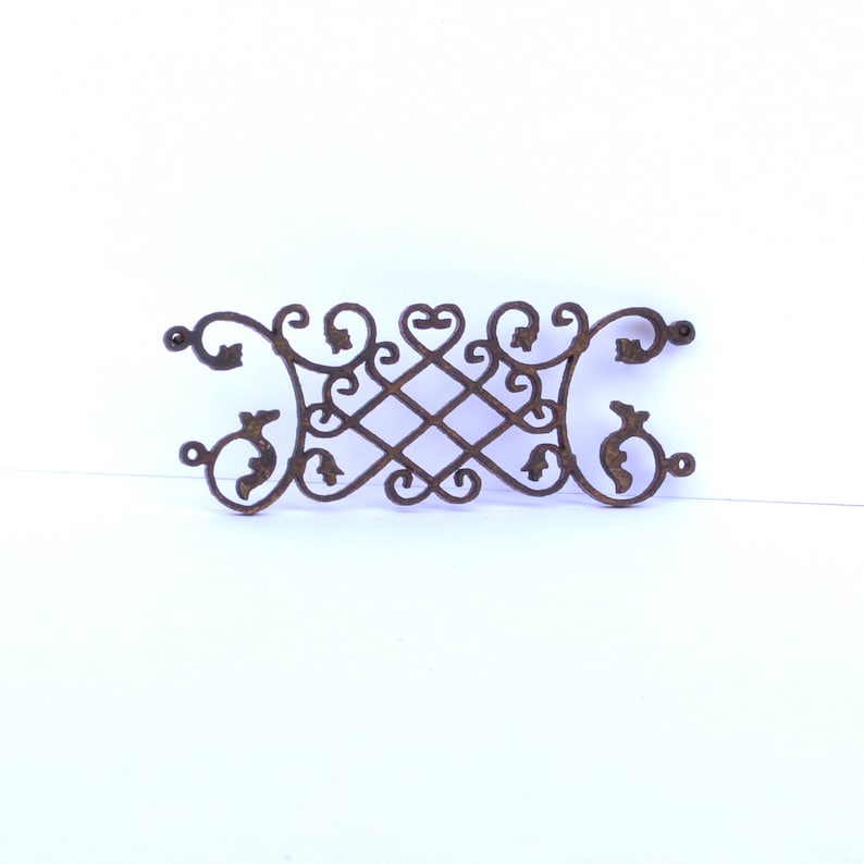 Puede incluir: Un dise&ntilde;o decorativo de volutas de metal con detalles intrincados. Las volutas est&aacute;n hechas de metal marr&oacute;n oscuro y tienen un aspecto vintage.