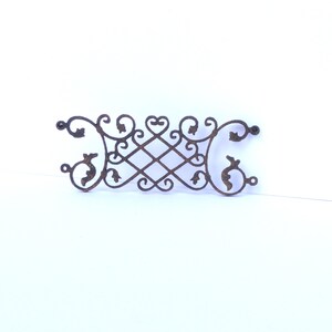 Puede incluir: Un dise&ntilde;o met&aacute;lico decorativo con intrincados trabajos de desplazamiento y motivos florales. El dise&ntilde;o est&aacute; hecho de metal oscuro y tiene un aspecto r&uacute;stico y antiguo.