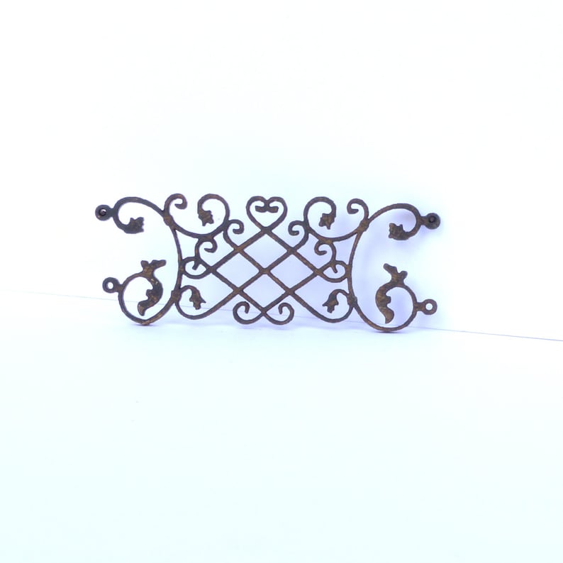 Puede incluir: Un dise&ntilde;o met&aacute;lico decorativo con intrincados trabajos de desplazamiento y motivos florales. El dise&ntilde;o est&aacute; hecho de metal oscuro y tiene un aspecto r&uacute;stico y antiguo.