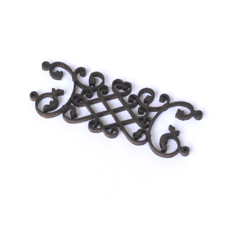 Puede incluir: Un adorno decorativo de madera marr&oacute;n oscuro con un dise&ntilde;o intrincado y ornamentado. El dise&ntilde;o presenta un patr&oacute;n repetitivo de espirales y bucles, creando una apariencia delicada y elegante.