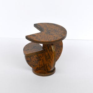 Puede incluir: Una mesa peque&ntilde;a de madera con un dise&ntilde;o geom&eacute;trico &uacute;nico. La mesa est&aacute; hecha de varias piezas de madera que se unen para crear una forma de espiral. La mesa est&aacute; pintada en un esquema de color marr&oacute;n y negro.