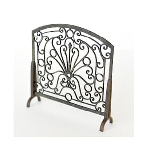 May include: A black metal fireplace screen with a decorative, ornate design. The screen has a curved top and stands on four legs.