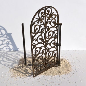 Puede incluir: Una puerta de metal decorativa con un dise&ntilde;o de desplazamiento. La puerta est&aacute; hecha de metal marr&oacute;n oscuro y tiene un aspecto r&uacute;stico. La puerta est&aacute; de pie sobre una superficie blanca.