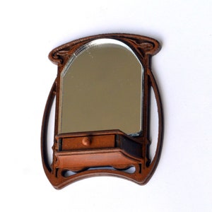 May include: A brown wooden wall-mounted mirror with an arched top and a small drawer underneath. The mirror has a decorative design around the frame.