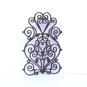 May include: A decorative metal wall panel with a brown finish. The panel features a repeating pattern of intricate swirls and scrolls.