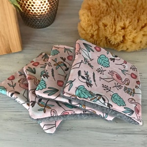 Könnte beinhalten: Vier rosa und graue Stoffuntersetzer mit einem Flamingo- und tropischen Blattmotiv.