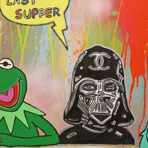 Pu&ograve; includere: Dipinto pop art con Kermit la Rana, Darth Vader e Beaker. Il casco di Darth Vader ha un logo Chanel. Le parole "LAST SUPPER" sono in un fumetto giallo. Lo sfondo presenta schizzi di vernice colorati.