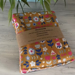 Könnte beinhalten: Ein Stapel Spültücher mit floralem Muster in Senfgelb, Rosa, Blau und Weiß. Die Spültücher sind mit einem braunen Papierband umwickelt, auf dem Text aufgedruckt ist. Das Blumenmuster umfasst stilisierte Blumen und Blätter.