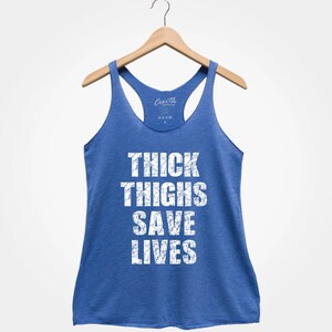 May include: A royal blue racerback tank top with the text "THICK THIGHS SAVE LIVES" printed in white.