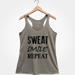 May include: A heather grey tank top with a black graphic that reads "Sweat Smile Repeat".