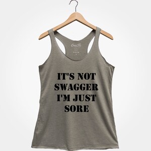 K&ouml;nnte beinhalten: Ein graues Tanktop mit dem Text "IT'S NOT SWAGGER I'M JUST SORE" in Schwarz gedruckt.